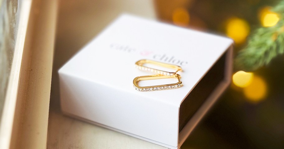 pair of gold square hoop earrings on top of a white jewelry box