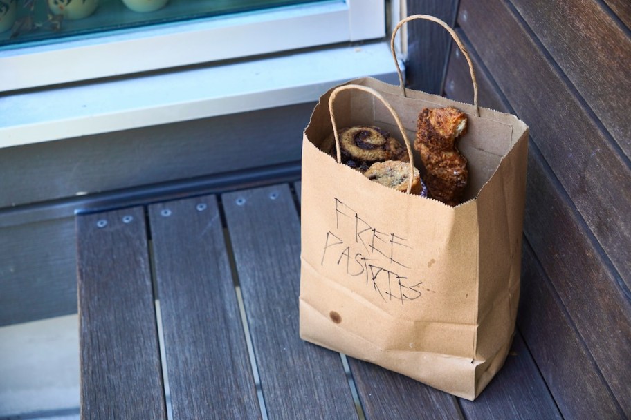 Brown bag of free pastry sitting on a bench 