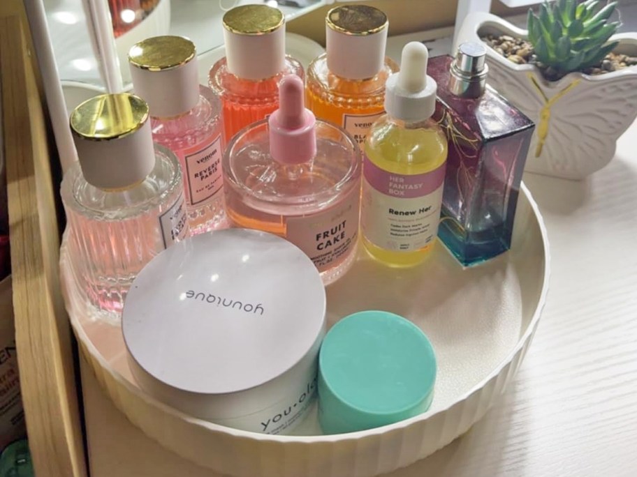perfumes and beauty products in a round white organizer on vanity