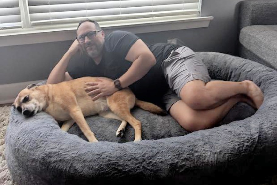 a man and dog in a large dog bed