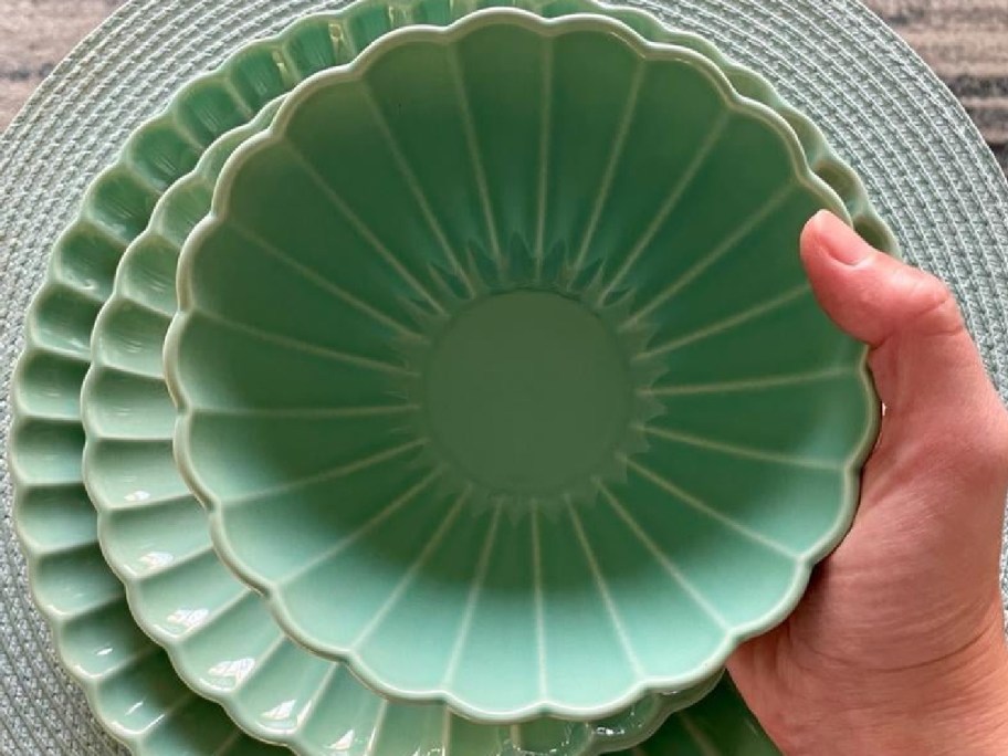 hand holding scallop bowl with other plates behind it 