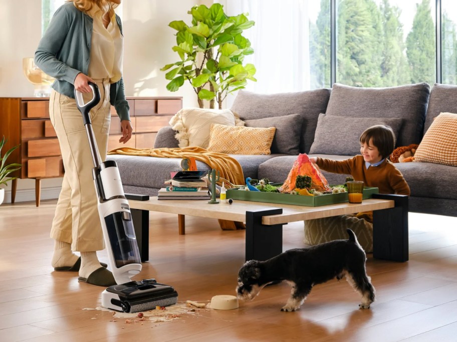 Woman mopping up a mess on Hardwood Floors in living room while child play
