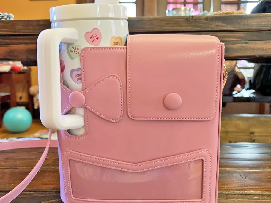 pink crossbody bag with a white tumbler inside