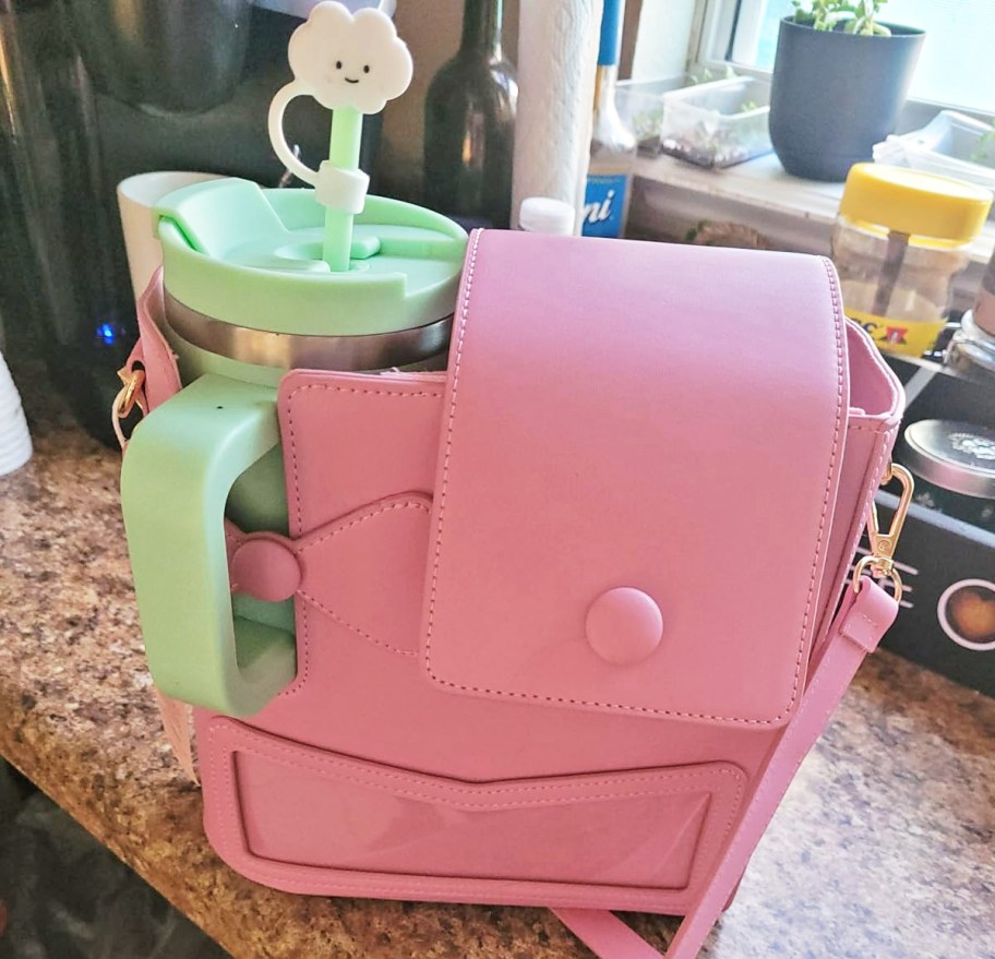 pink crossbody bag with a mint green tumbler inside