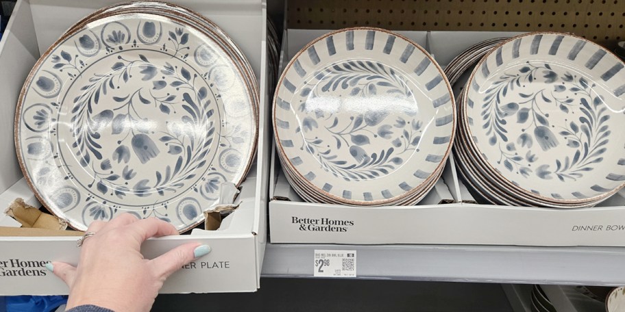 hand reaching for dinner plate and bowls on shelf in store