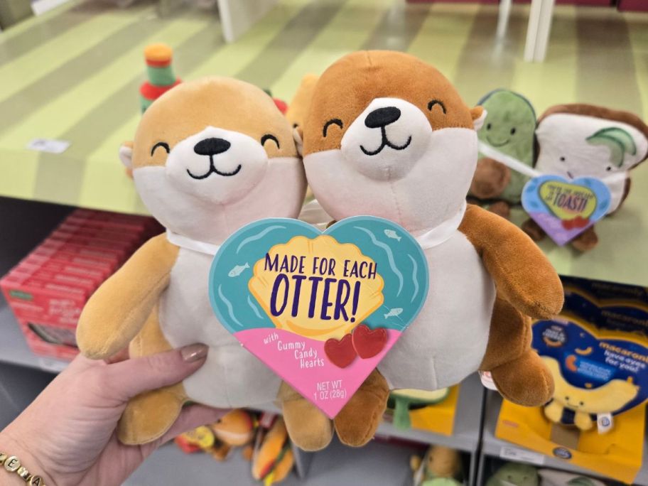 a womans hand holding an otter valentines plush duo