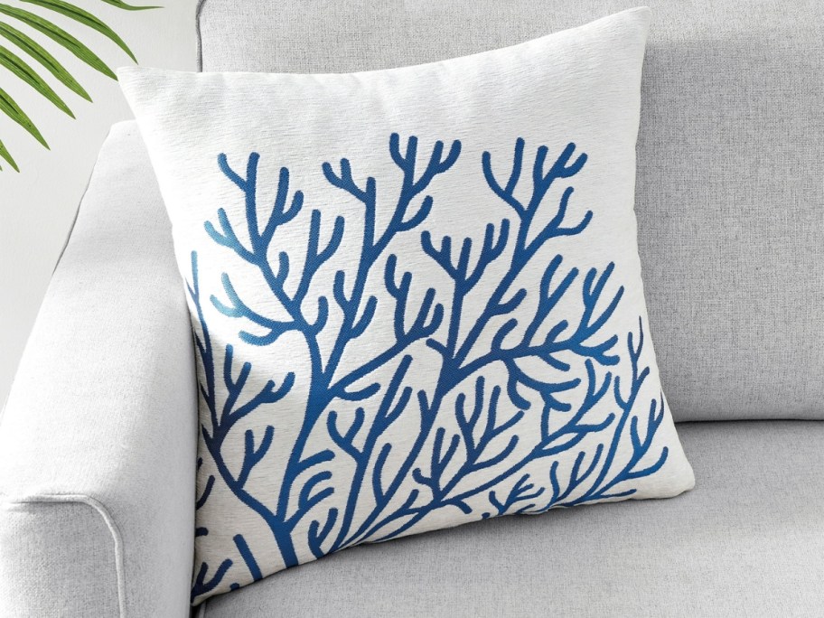 a throw pillow with a coral pattern on a couch