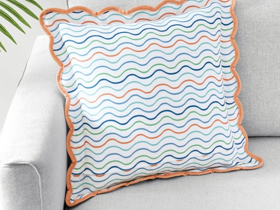 an orange, blue, and white striped throw pillow on a couch