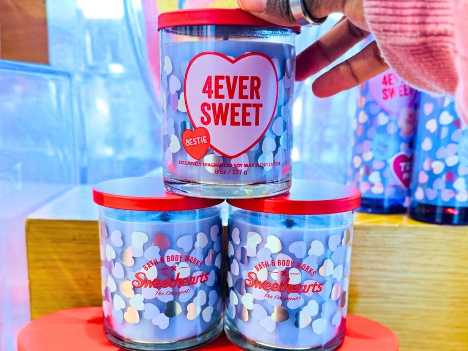 3 Bath & Body Works 4EVER Sweet Single Wick Candle with a human hand touching the top of one of the jars