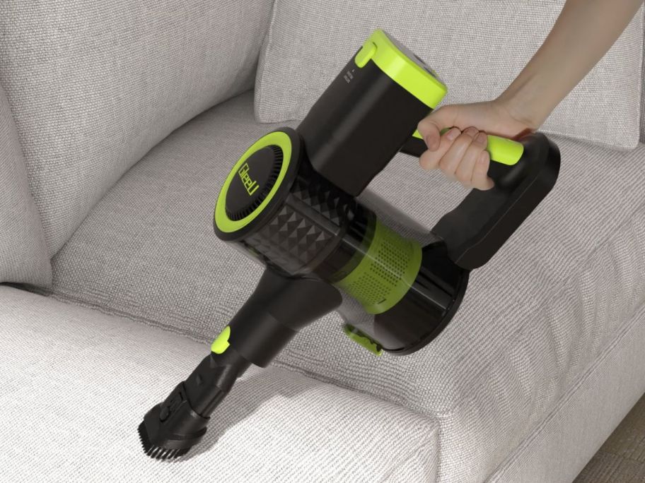 hand using a GleeU Cordless Stick Vacuum Cleaner on a couch