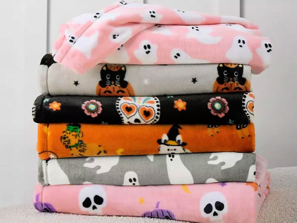 Pile of Halloween, throw blankets stacked on top of each other on top of bench
