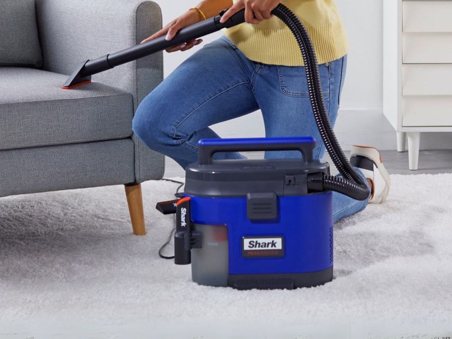 person using Shark MessMaster Wet/Dry Portable Vacuum w/ Bare Floor Tool on couch