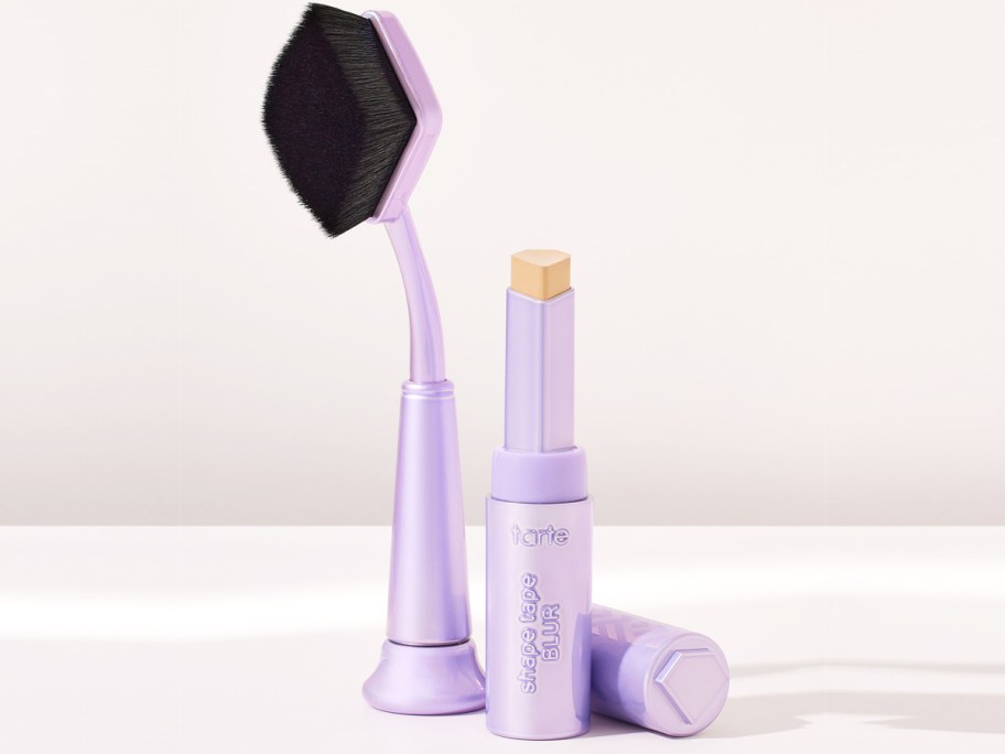 purple makeup brush and tube of concealer
