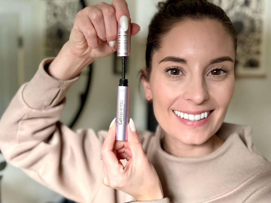 Woman holding tarte mascara up to her face showing the volume in her lashes