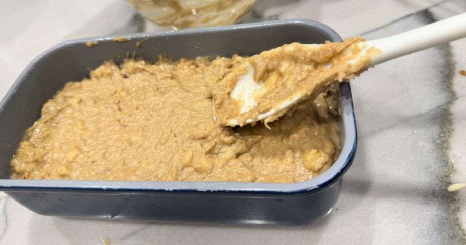 adding banana bread batter to a loaf pan