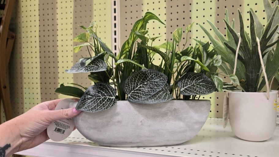 a womans hand reaching for an artificial plant