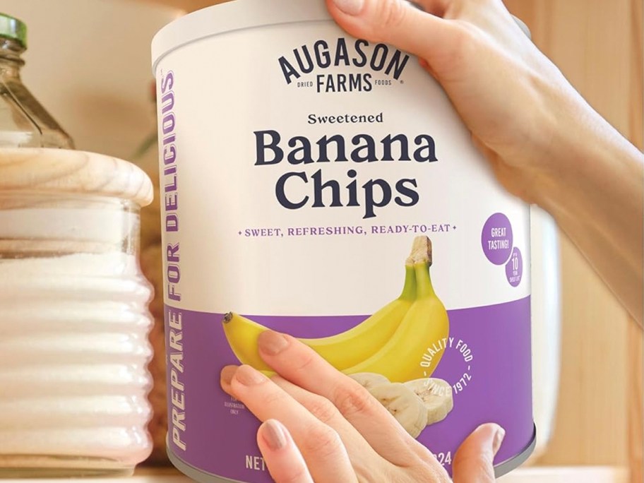 hands reaching for auguson farms banana chips can 