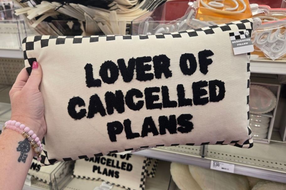 a woman hand holding a pillow that reads 'Lover of cancelled plans'
