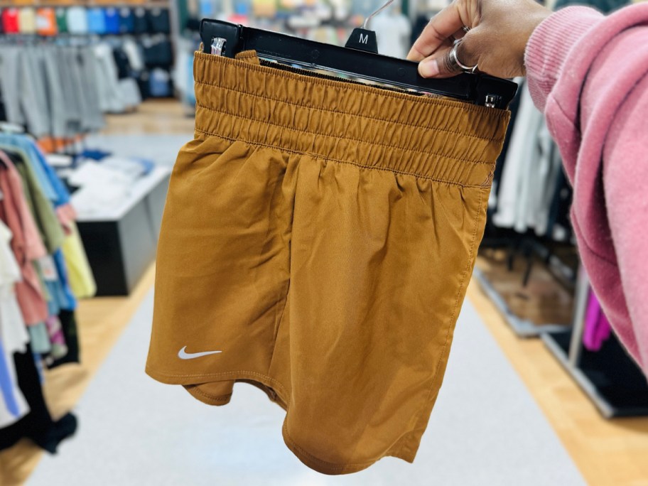 hand holding pair of brown nike shorts