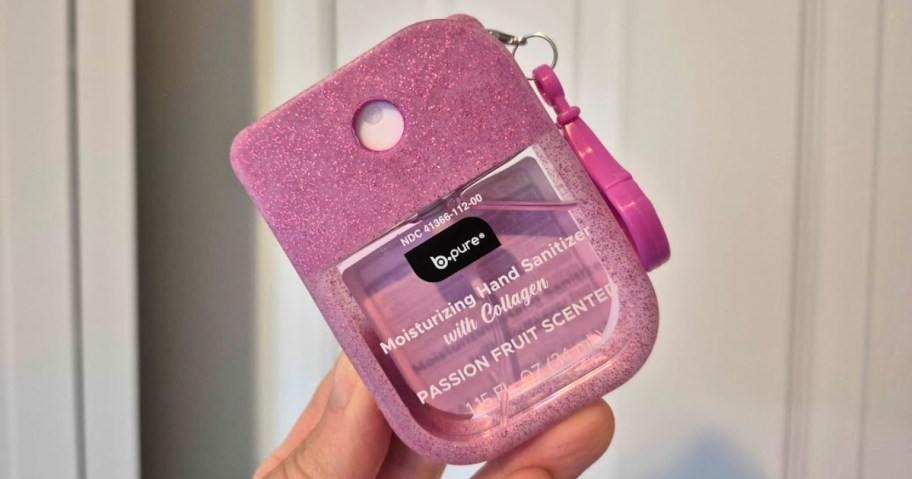 hand holding a small hand sanitizer container in a case with a carry strap
