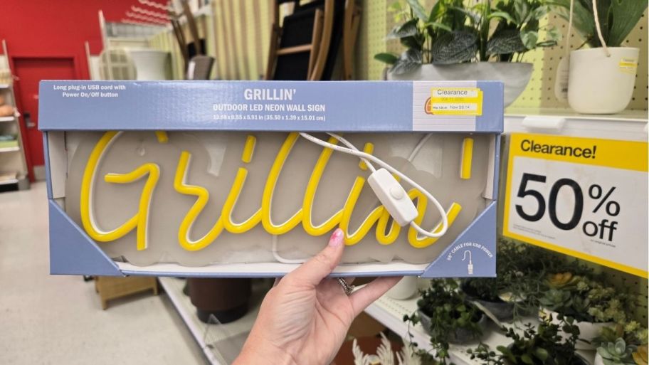 a woman's hand holding a faux neon sign.