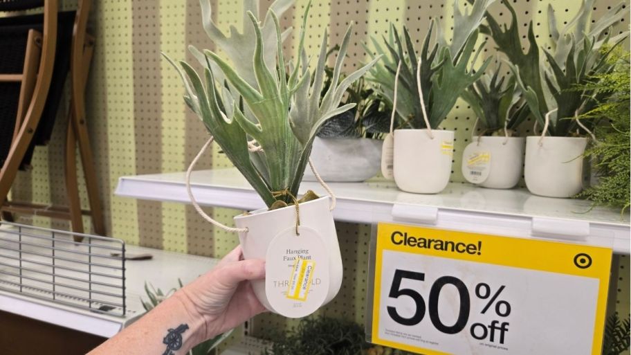 a womans hand holding an artificial plant