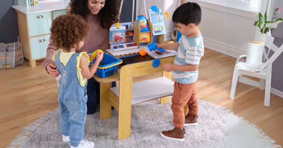 kids and mom playing with KidKraft Wooden Grocery Store Self-Checkout Center Playset