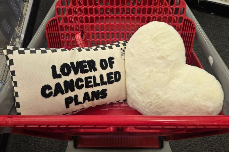 a black and white lumbar pillow and white faux fur heart pillow in a target shopping cart