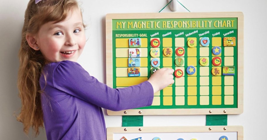 girl putting magnets on chore chart 