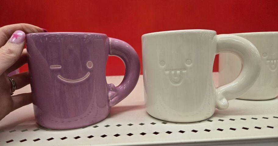 a pink and a white Room Essentials Novelty Face Mug on shelf in store