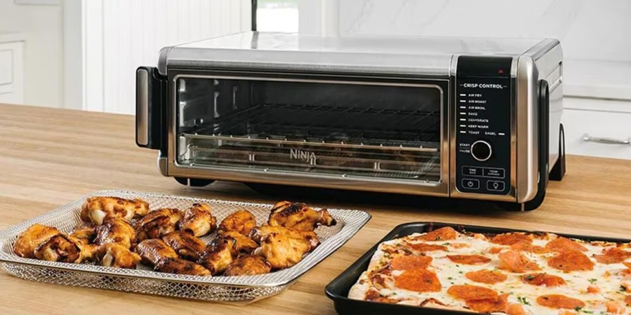ninja foodi air fryer on table with wings and pizza