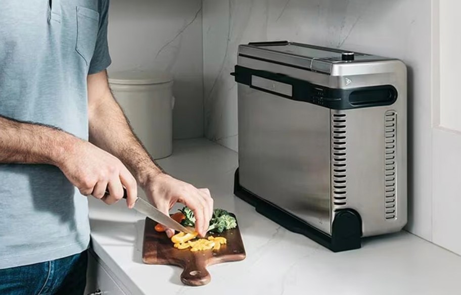 man cutting food on table with ninja air fryer in front of him