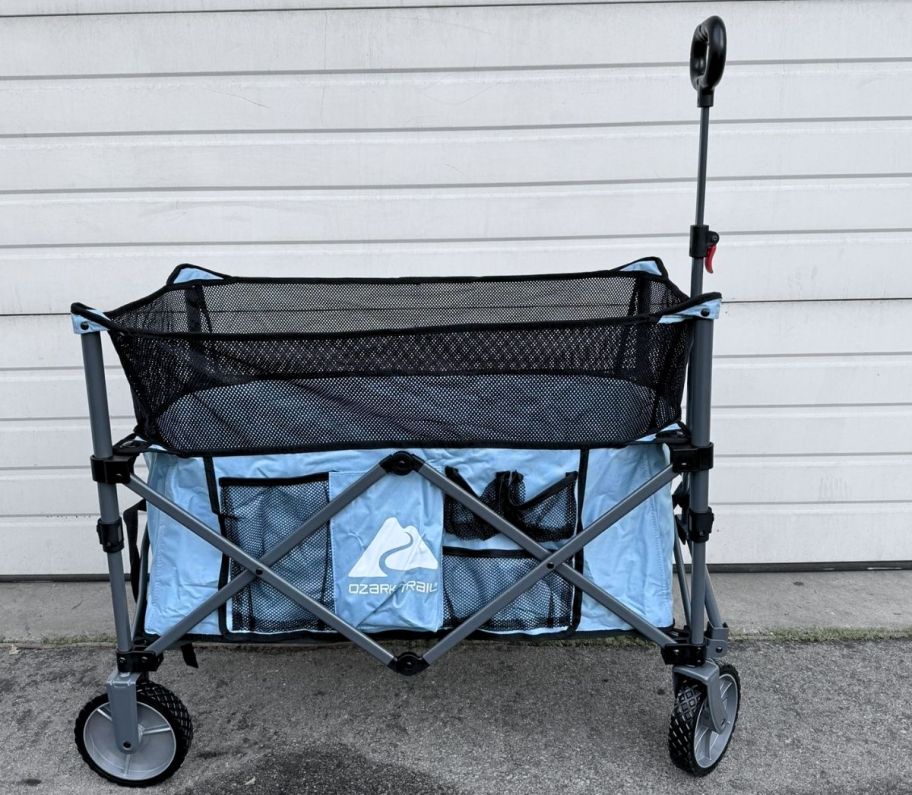 a light blue foldable wagon with telescoping handle