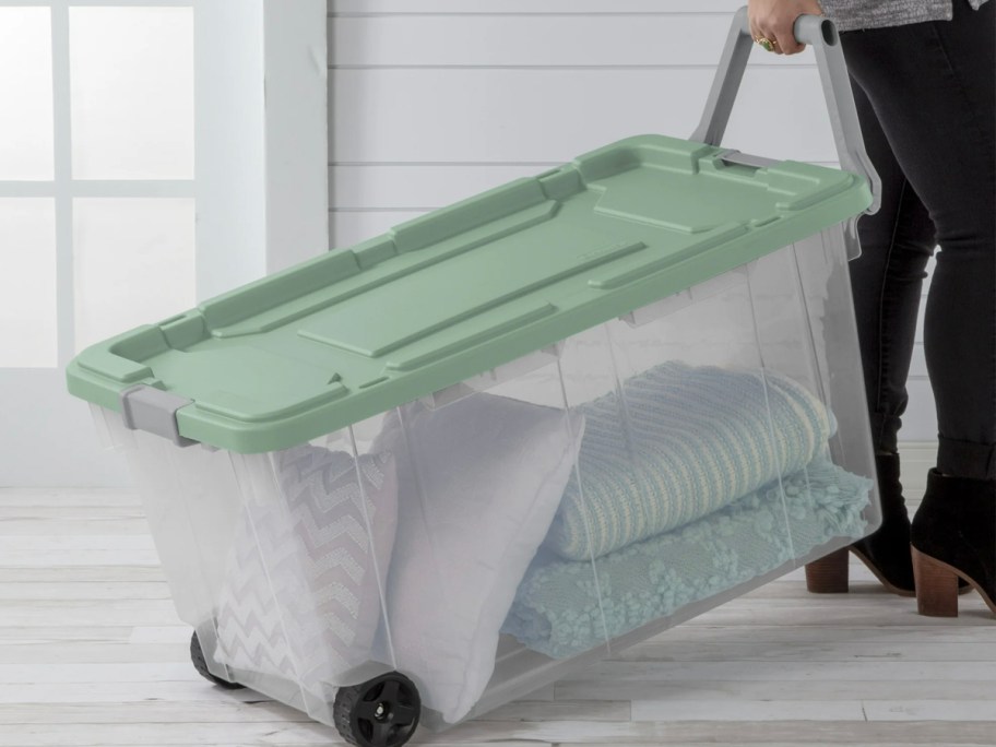 woman pulling green storage box on wheels