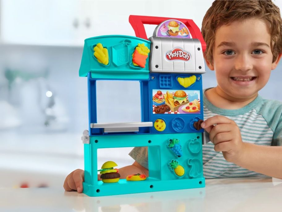 kid holding Play-Doh Busy Chefs Restaurant Playset on table