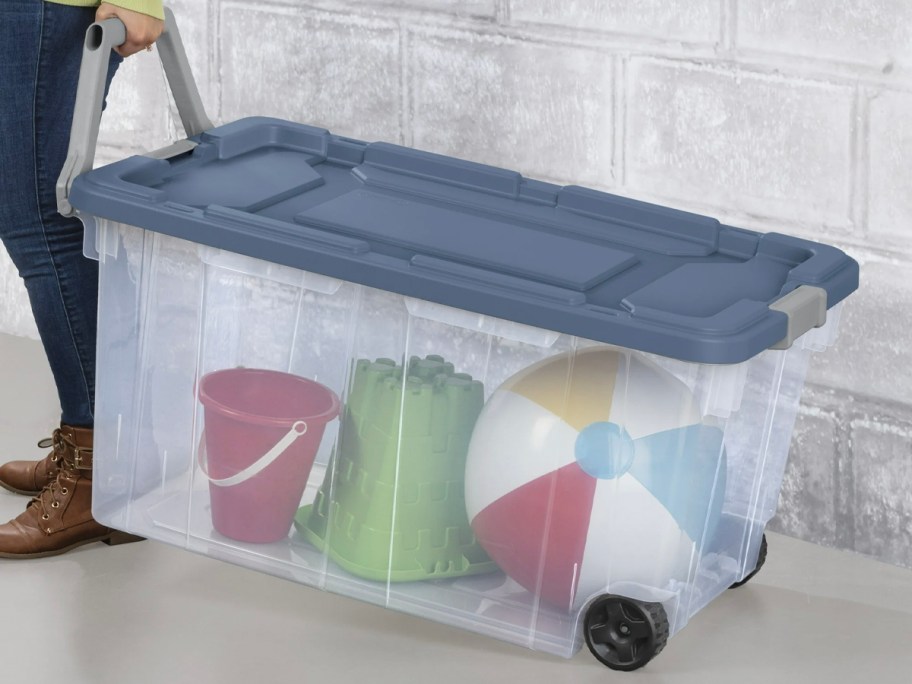 woman pulling blue storage box on wheels