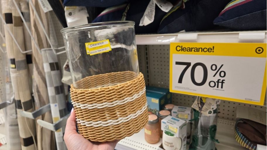 a woman's hand holding a wicker wrapped glass candle lantern