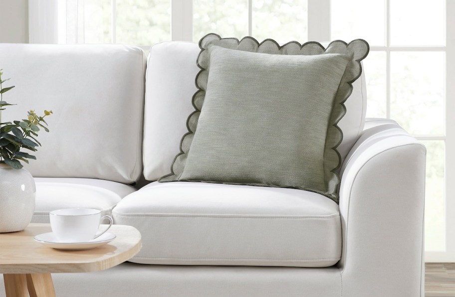 sage green scalloped pillow on beige sofa