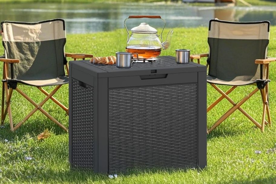 a resin deck box with 2 directors chairs next to a lake