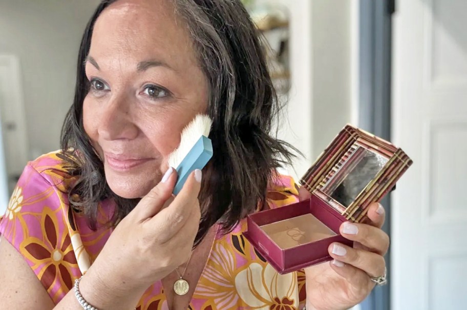 woman applying bronzer to face