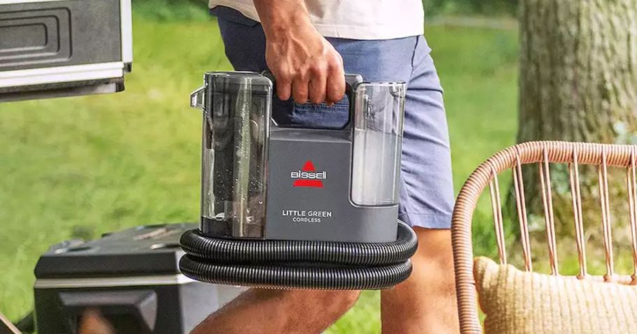 man carrying Bissell Little Green Cordless Portable Carpet Cleaner outside