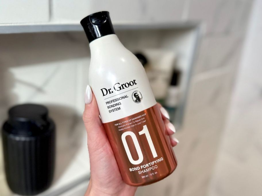 Hand holding a bottle of Dr. Groot Professional Bonding System #1 Shampoo