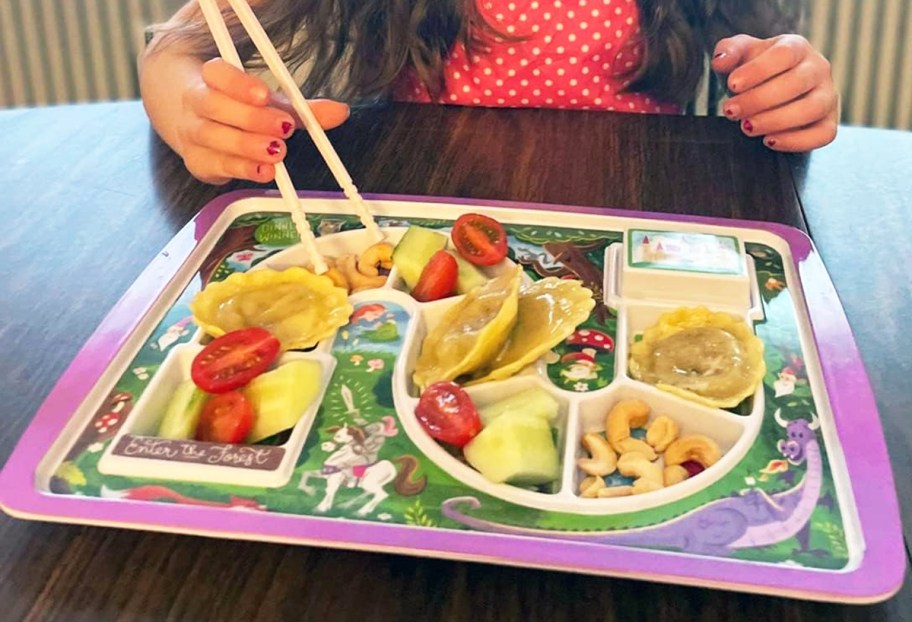 girl using chopsticks to grab food from tray