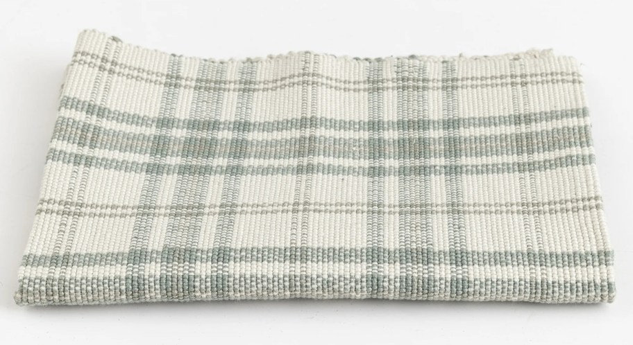 folded sage green and cream plaid doormat rug