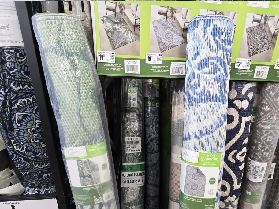 two rolled up outdoor rugs leaning against store display