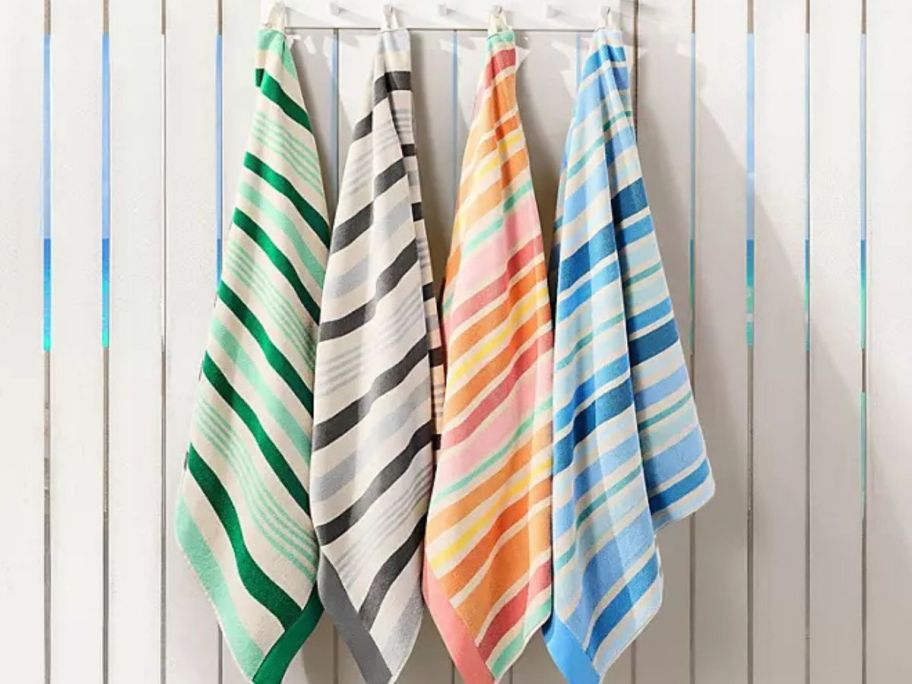 4 Member's Mark Kids Sand-Resistant Beach Towels hanging on a fence