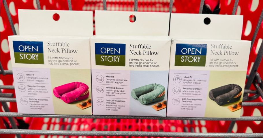 A Target shopping cart with 3 different color open story packable travel pillows in the front basket