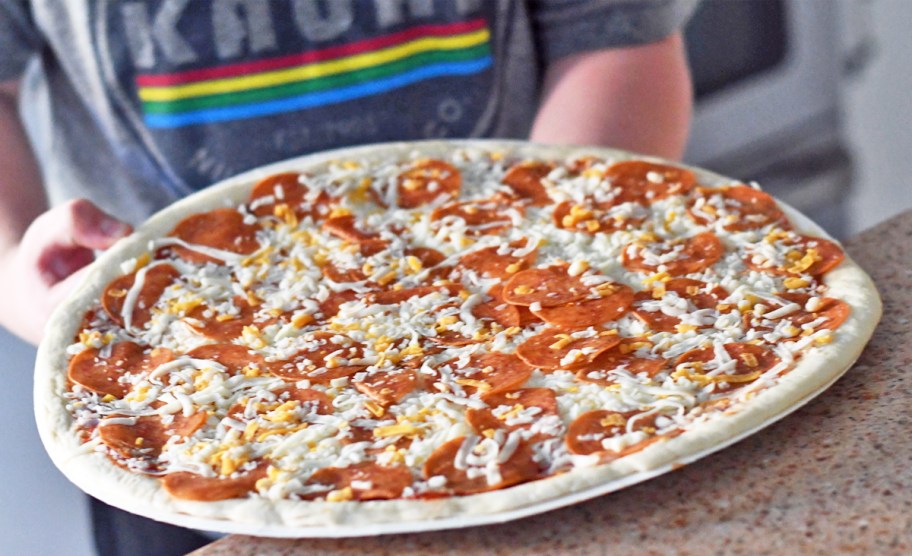 boy holding an uncooked pepperoni Papa Murphy’s Pizza