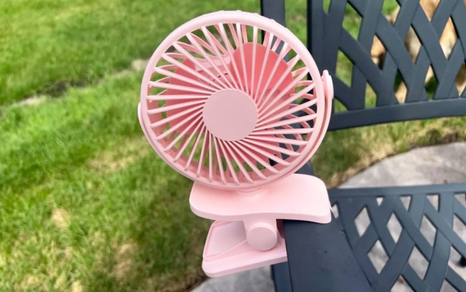 pink fan clipped onto arm of patio chair