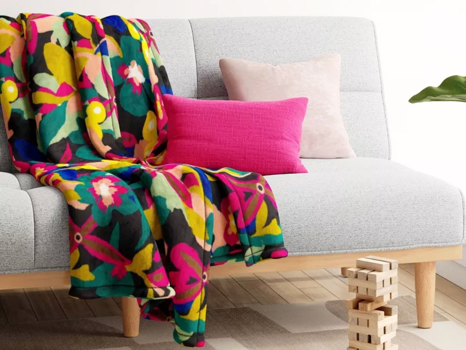 colorful throw blanket on couch with pink throw pillow